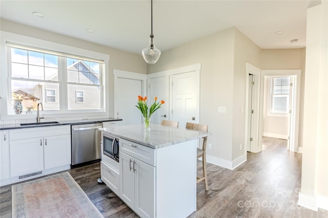 kitchen with a center island, pendant lighting, sink, appliances with stainless steel finishes, and white cabinets