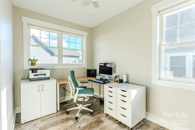 home office with light wood-type flooring and a healthy amount of sunlight