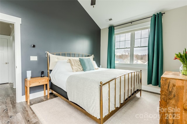 bedroom with ceiling fan, light hardwood / wood-style flooring, and lofted ceiling