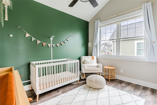 bedroom featuring ceiling fan, lofted ceiling, a crib, and hardwood / wood-style flooring