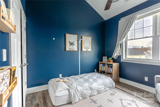 bedroom with ceiling fan, vaulted ceiling, multiple windows, and hardwood / wood-style floors