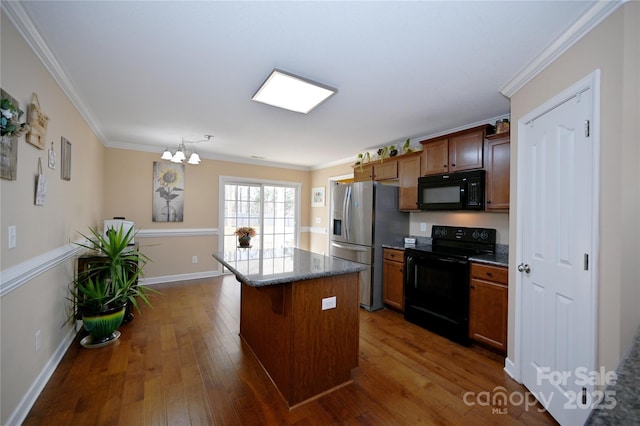 kitchen featuring black appliances, a kitchen island, dark hardwood / wood-style flooring, an inviting chandelier, and ornamental molding