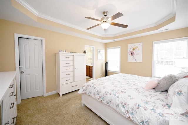 bedroom featuring ceiling fan, ensuite bathroom, light colored carpet, and a raised ceiling