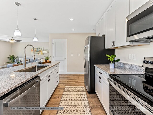 430 Hague Dr, Columbus, NC 28722 - kitchen featuring stainless steel appliances, a sink, white cabinets, light wood-type flooring, and decorative light fixtures