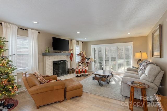 living room with a fireplace, a healthy amount of sunlight, and light wood-type flooring