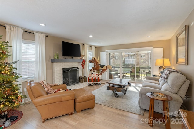 living room with a fireplace, light wood-type flooring, and a wealth of natural light