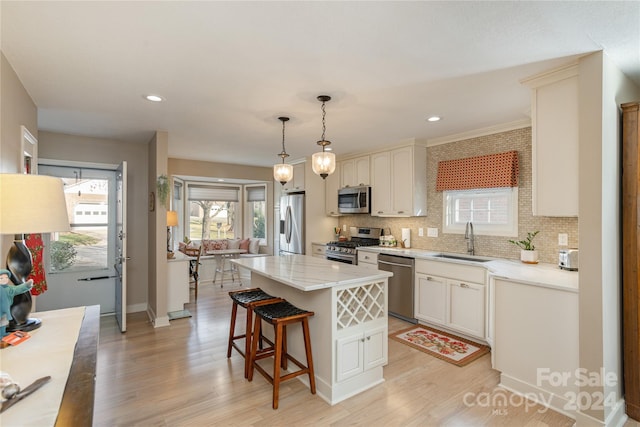 kitchen featuring light wood-type flooring, stainless steel appliances, sink, pendant lighting, and a center island