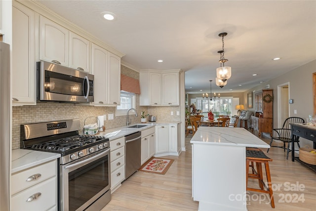 kitchen featuring a kitchen breakfast bar, sink, light hardwood / wood-style floors, appliances with stainless steel finishes, and a kitchen island