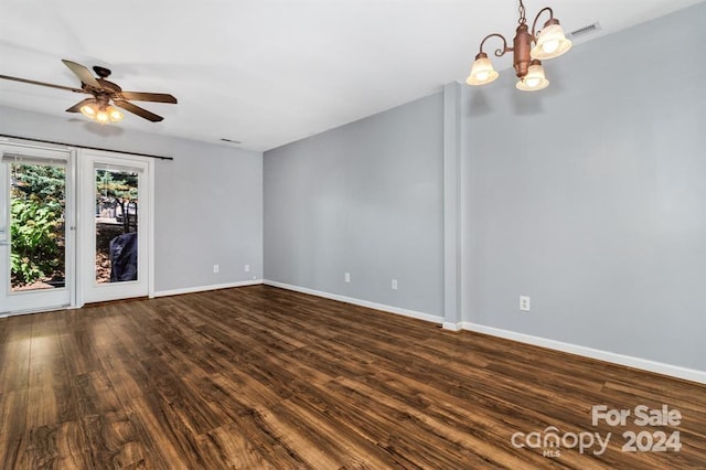 empty room with ceiling fan with notable chandelier and dark wood-type flooring