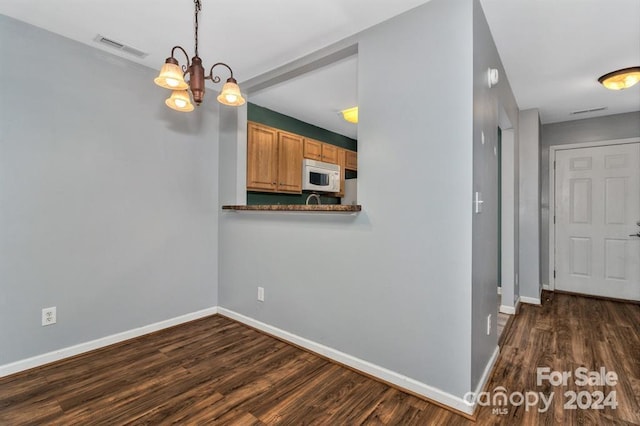 kitchen featuring decorative light fixtures, an inviting chandelier, and dark wood-type flooring