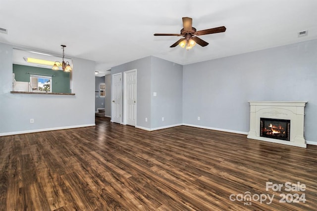 unfurnished living room featuring dark hardwood / wood-style floors and ceiling fan with notable chandelier