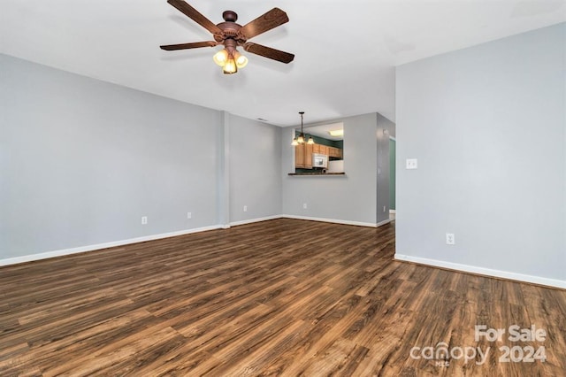 unfurnished living room with dark hardwood / wood-style floors and ceiling fan with notable chandelier