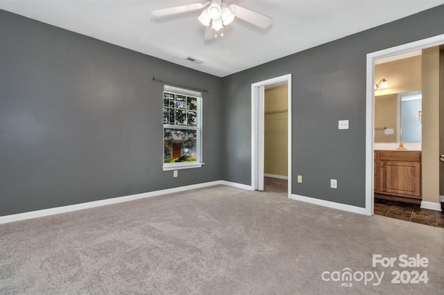 unfurnished bedroom with carpet flooring, ensuite bath, ceiling fan, sink, and a closet