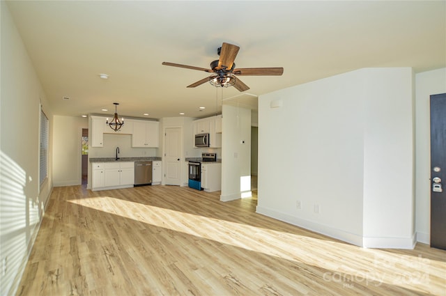 unfurnished living room with ceiling fan with notable chandelier, light hardwood / wood-style flooring, and sink