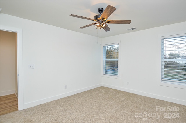 carpeted spare room featuring ceiling fan and a healthy amount of sunlight