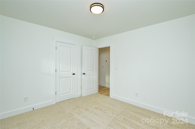 unfurnished bedroom featuring light colored carpet and a closet