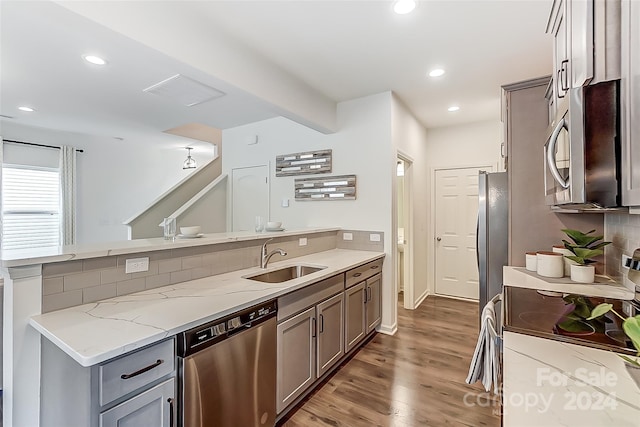 kitchen featuring light stone countertops, sink, dark hardwood / wood-style flooring, backsplash, and appliances with stainless steel finishes