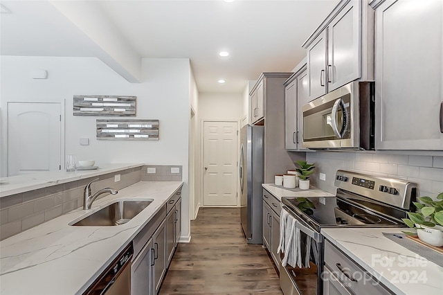 kitchen featuring gray cabinetry, sink, dark wood-type flooring, stainless steel appliances, and light stone counters