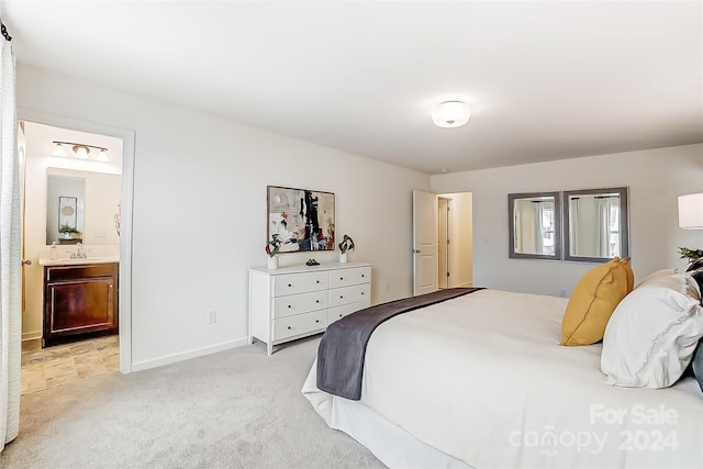 bedroom with ensuite bathroom, light colored carpet, and sink