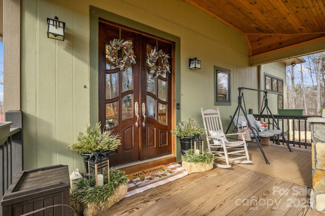 property entrance with covered porch and french doors