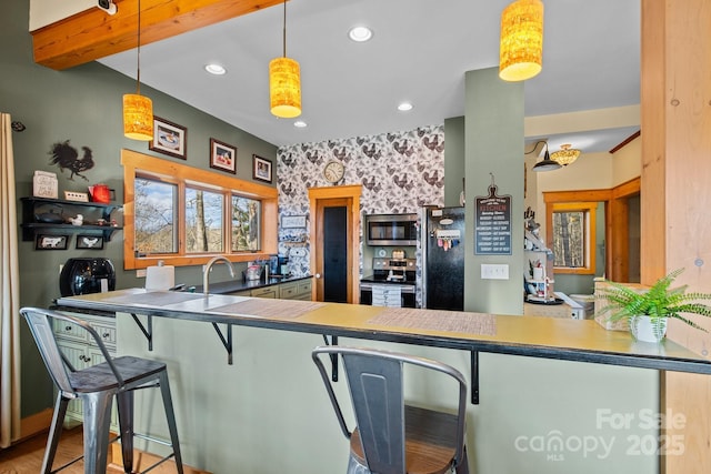 kitchen with pendant lighting, appliances with stainless steel finishes, beam ceiling, a kitchen bar, and kitchen peninsula