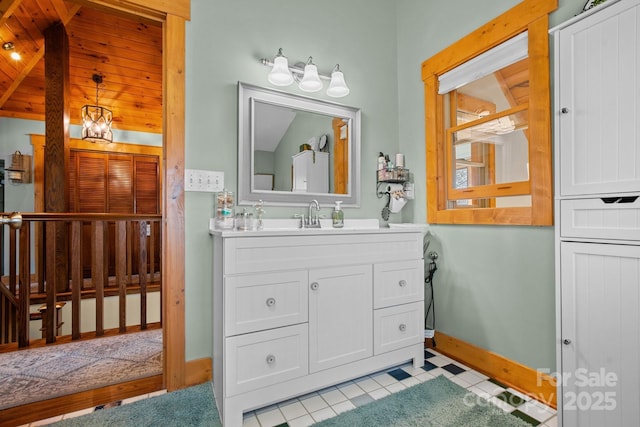 bathroom with tile patterned floors, vanity, a chandelier, and vaulted ceiling