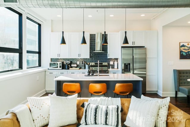 kitchen featuring pendant lighting, wall chimney exhaust hood, appliances with stainless steel finishes, and a wealth of natural light