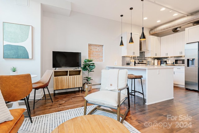 kitchen with decorative backsplash, appliances with stainless steel finishes, pendant lighting, white cabinets, and dark hardwood / wood-style floors