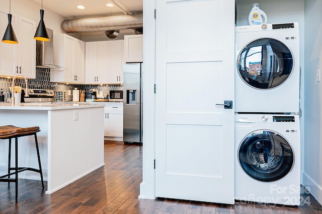 clothes washing area with dark hardwood / wood-style floors and stacked washer and clothes dryer