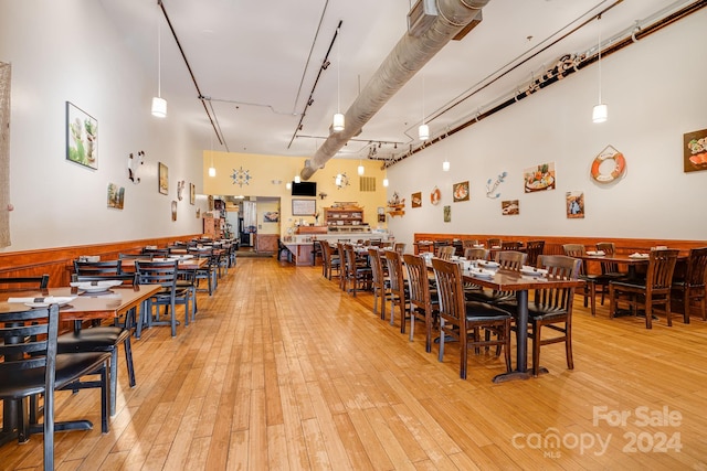 dining area featuring light hardwood / wood-style floors and a high ceiling