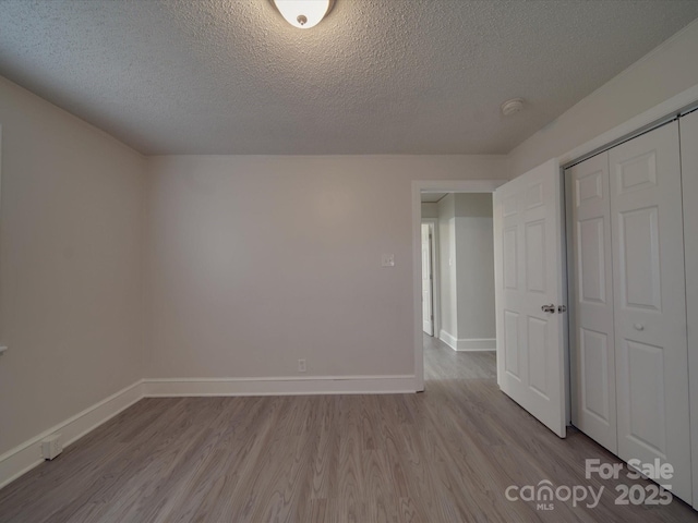 unfurnished bedroom with a closet, a textured ceiling, and light wood-type flooring