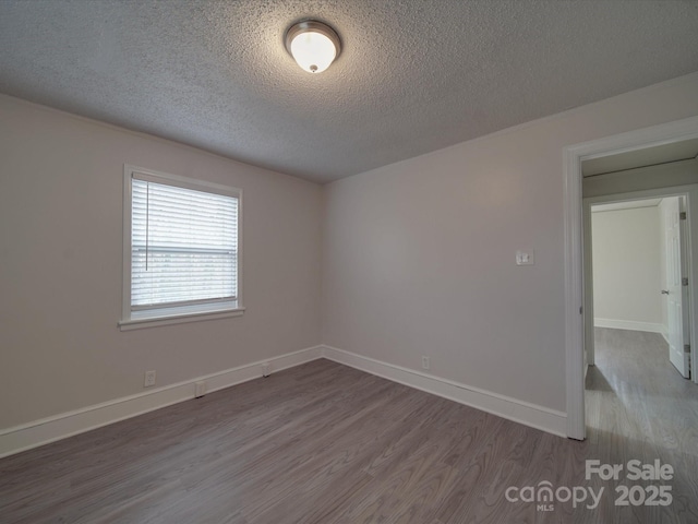 spare room featuring hardwood / wood-style floors and a textured ceiling