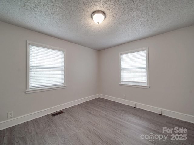 unfurnished room with hardwood / wood-style flooring and a textured ceiling