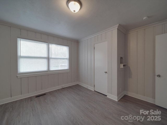 unfurnished room featuring crown molding and light wood-type flooring