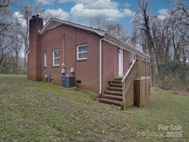 view of side of property featuring central AC unit and a lawn