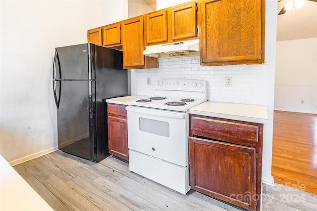 kitchen with black refrigerator, decorative backsplash, light wood-type flooring, and white electric stove