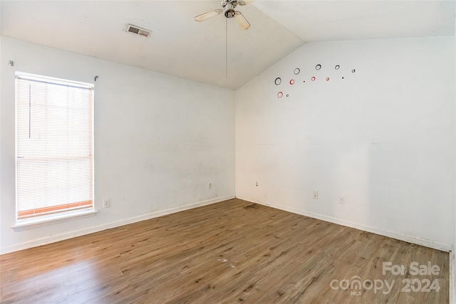 empty room featuring hardwood / wood-style flooring, ceiling fan, and vaulted ceiling