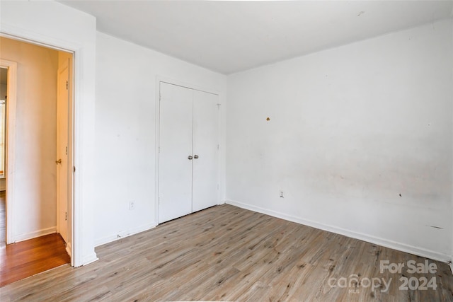 unfurnished bedroom with a closet and light wood-type flooring