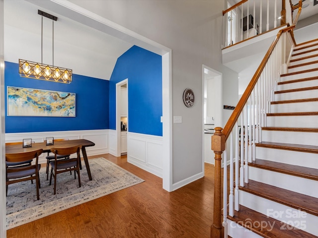 foyer featuring hardwood / wood-style floors, vaulted ceiling, and a notable chandelier