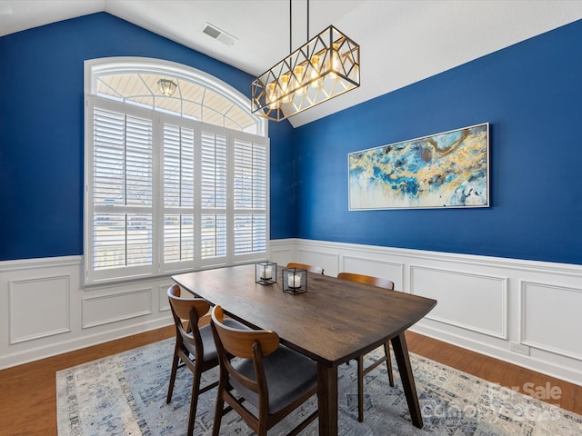 dining space featuring hardwood / wood-style flooring, an inviting chandelier, and lofted ceiling