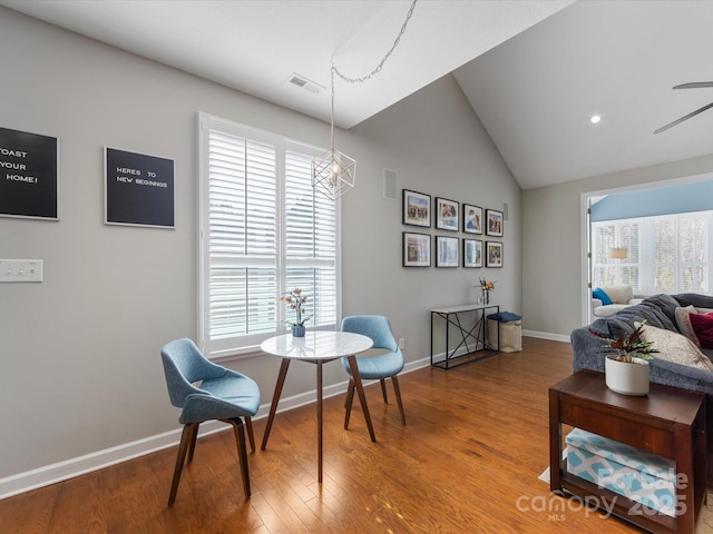 sitting room with hardwood / wood-style flooring, ceiling fan with notable chandelier, and vaulted ceiling