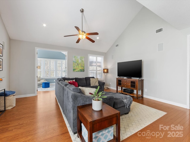 living room with hardwood / wood-style floors, high vaulted ceiling, and ceiling fan