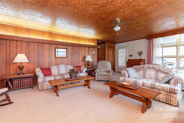 living room with ceiling fan, carpet floors, and wooden walls