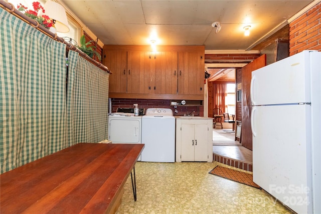 laundry area featuring washer and clothes dryer, wood walls, cabinets, and sink