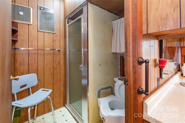 bathroom with tile patterned floors, toilet, a shower with shower door, and wooden walls