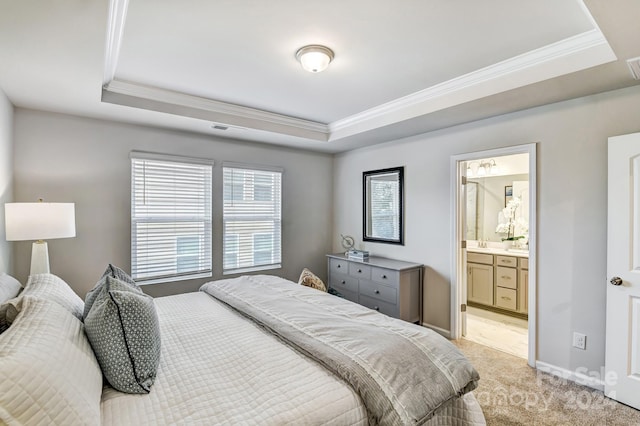 carpeted bedroom with a tray ceiling, ensuite bath, and crown molding