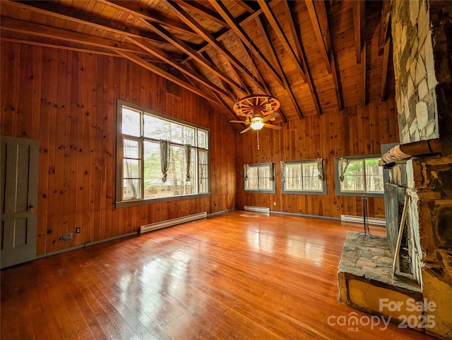 unfurnished living room featuring a healthy amount of sunlight, hardwood / wood-style flooring, and a baseboard radiator