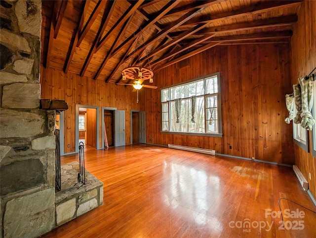 unfurnished living room with lofted ceiling with beams, a baseboard heating unit, wooden walls, and wooden ceiling