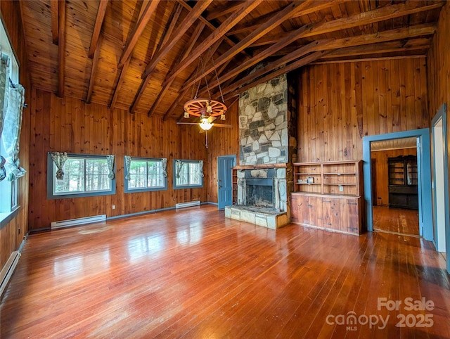 unfurnished living room featuring hardwood / wood-style floors, wooden walls, wooden ceiling, a fireplace, and baseboard heating