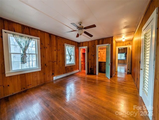 unfurnished room featuring hardwood / wood-style floors, a ceiling fan, and baseboard heating